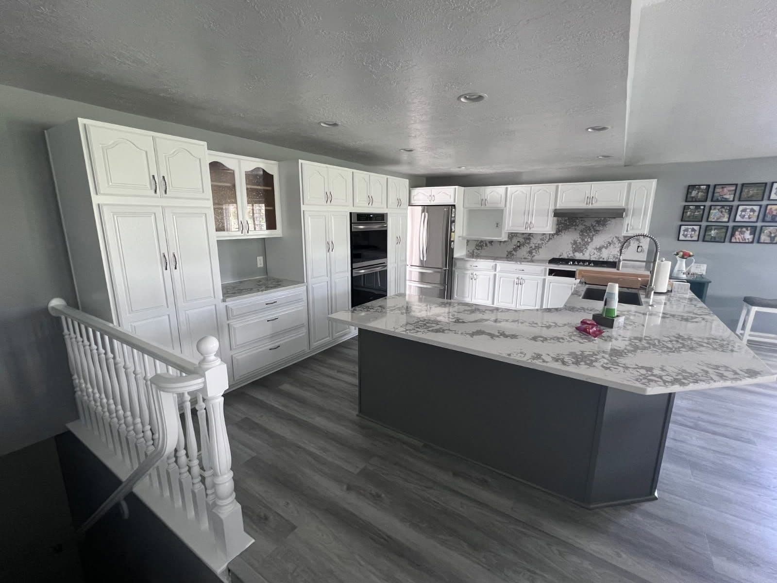Large open kitchen with white-painted cabinets and a gray-painted island under a quartz countertop.