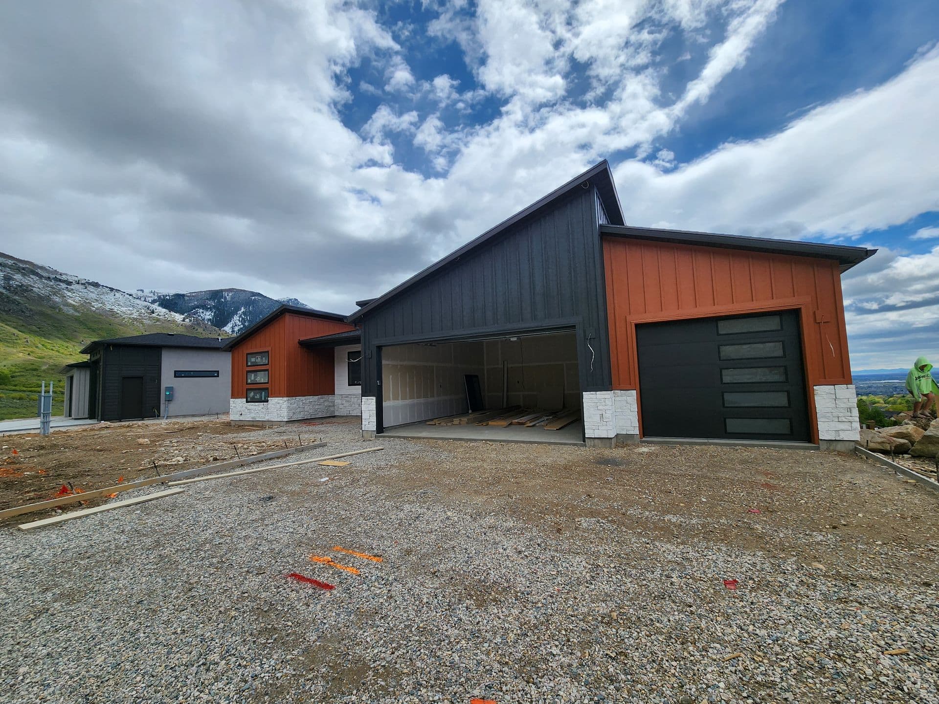 Freshly painted modern black-and-rust board-and-batten home against snow-capped Utah mountains.